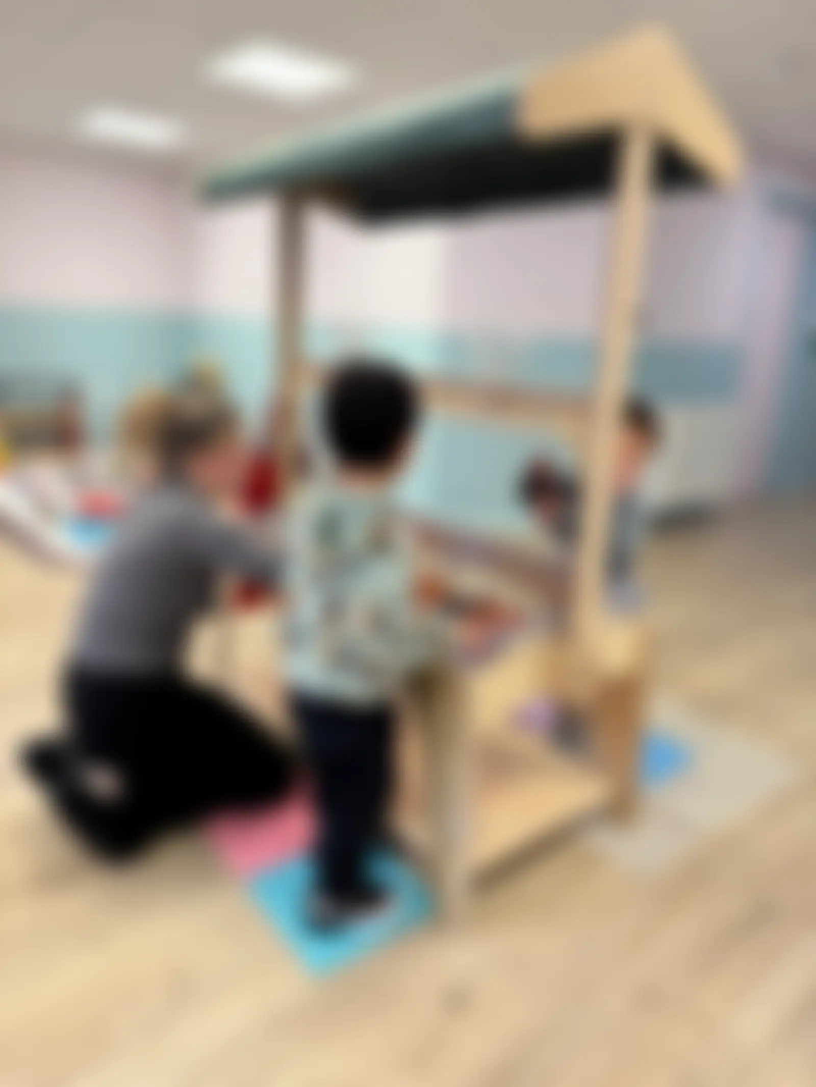 Practitioner kneeling beside children at the water-play unit